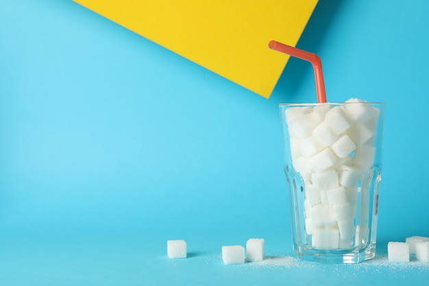 Verre avec des morceaux de sucre et de la paille sur fond bicolore, espace pour le texte