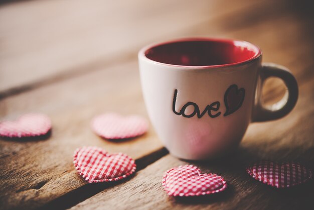 Verre avec les mots "Love" placé sur le plancher en bois