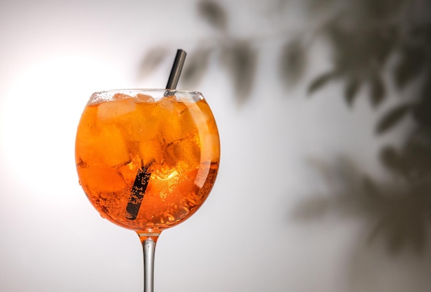 Verre d'orange aperol spritz cocktail sur fond de feuilles défocalisées