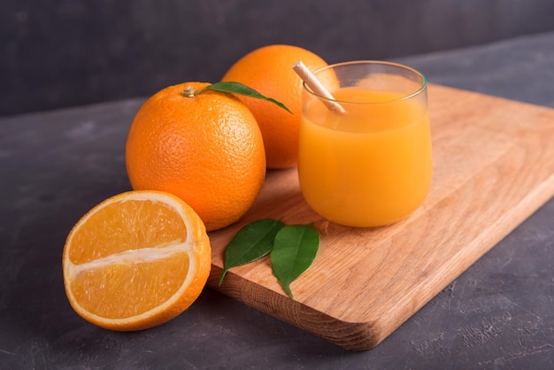 Photo verre d'orange et de jus et tranche de fruit orange sur un bureau en bois