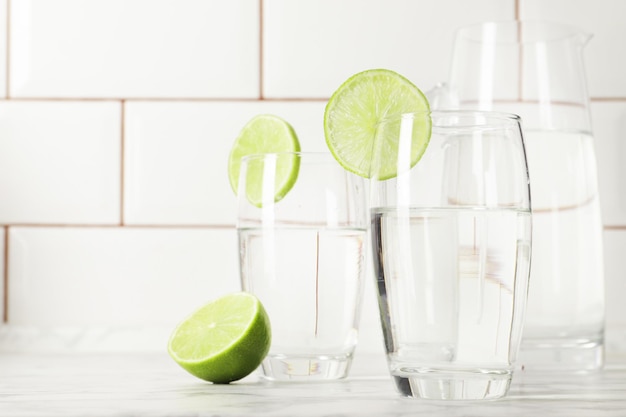 Verre et pichet avec de l'eau douce et de la chaux sur une table en marbre Espace pour le texte