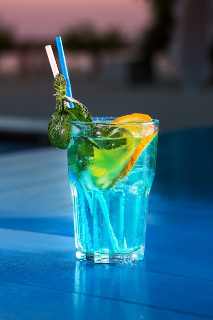 Verre de plan rapproché de cocktail de lagon bleu au fond de compteur de barre d'été