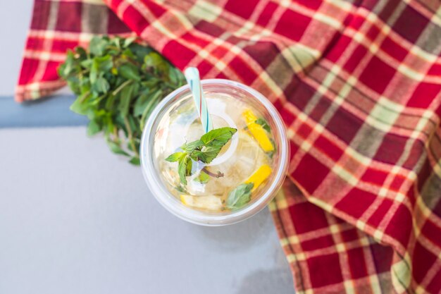 Un verre en plastique avec un tube de mojito à la menthe et citron sur la table