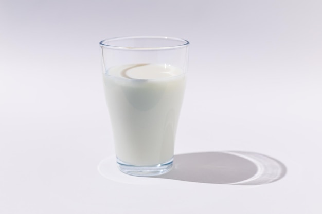 Verre plein verre de lait en lumière dure sur fond BLANC Pénurie de produits laitiers calcium croître et boire concept