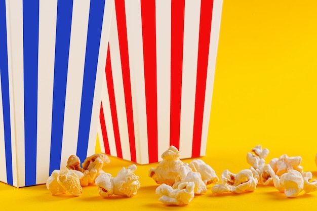 Photo verre avec pop-corn sur fond jaune