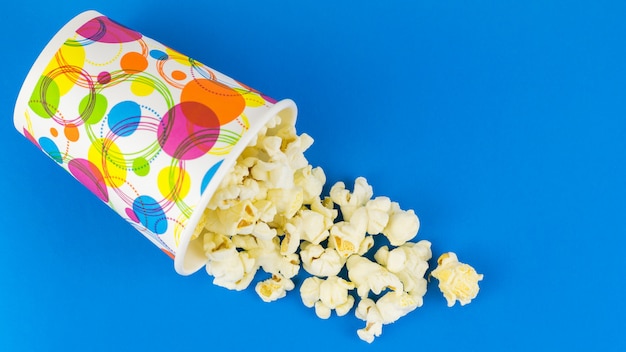 Verre de pop-corn multicolore inversé sur une table bleue