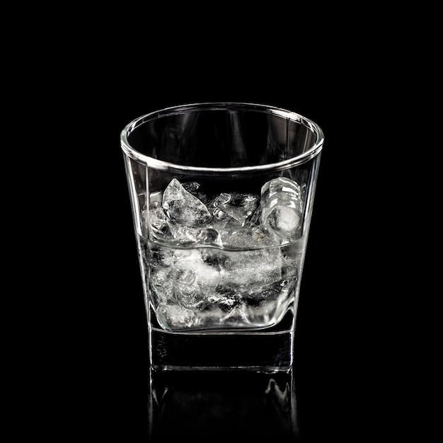 Verre pour alcool avec de la glace pure isolé sur fond noir