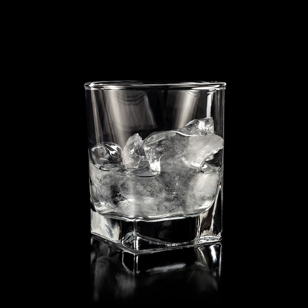 Verre pour alcool avec de la glace pure isolé sur fond noir