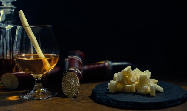 Verre de rhum de canne avec des morceaux de canne sur une table en bois rustique et fond sombre