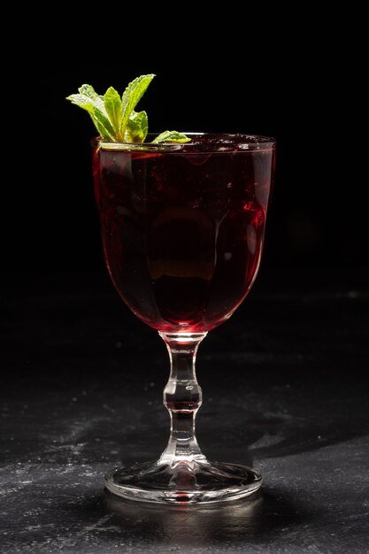 Verre de sangria au vin rouge avec des feuilles de menthe sur fond noir