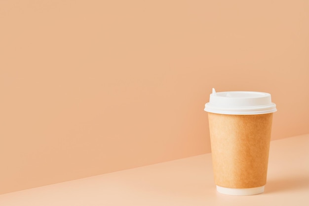 Verre sans marque en papier pour boissons avec couvercle blanc sur fond coloré, gros plan avec espace de copie pour le texte. Tasse à café écologique en carton