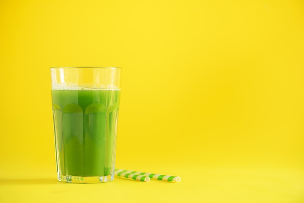 Verre de smoothie au céleri vert sur fond jaune