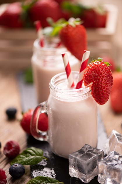 Verre de smoothie aux fraises sur fond de bois close up