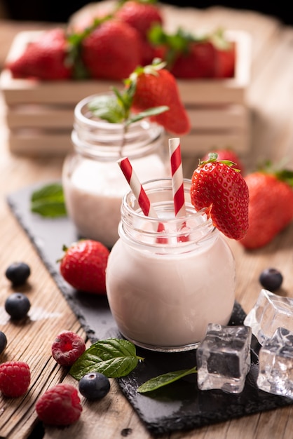 Verre de smoothie aux fraises sur fond de bois close up