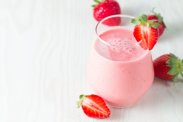Un verre de smoothie aux fraises fraîches sur un fond de bois