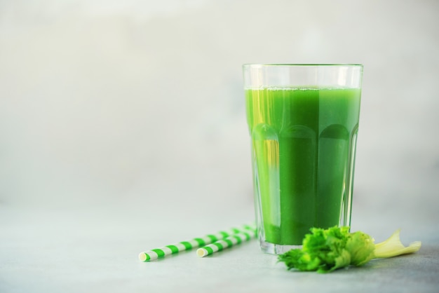 Verre de smoothie de céleri vert sur fond de béton gris