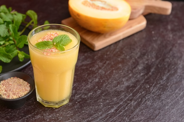 Verre avec smoothie melon sur fond de bois foncé