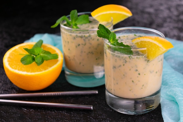 Un verre de smoothie à la menthe orange sur fond noir