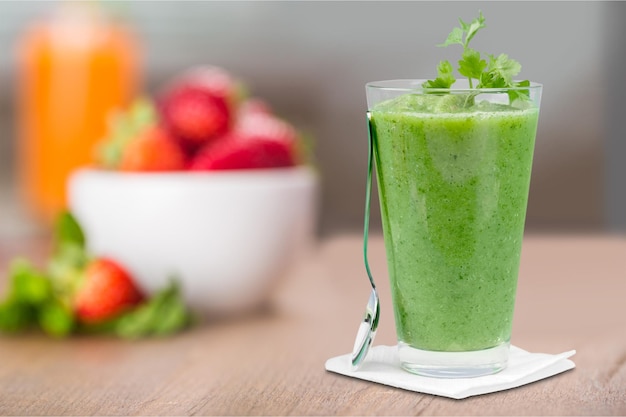 Verre de smoothie vert frais sur table en bois