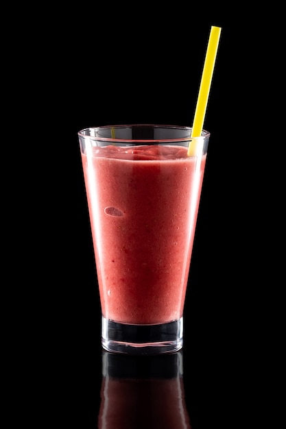 Verre de smoothies froids frais avec de la paille isolée sur fond noir