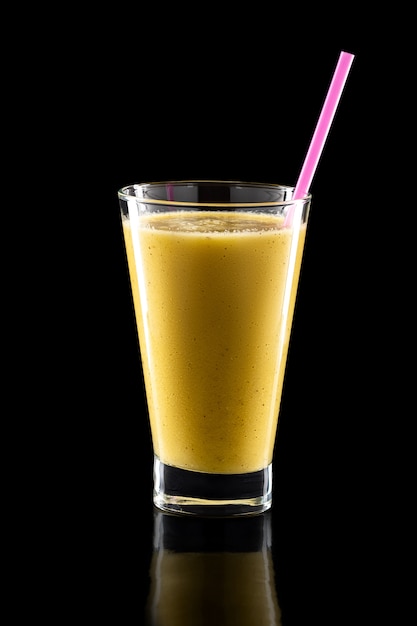 Verre de smoothies froids frais avec de la paille isolée sur fond noir