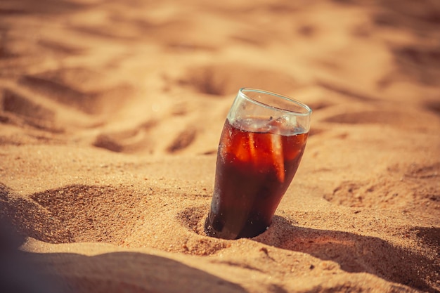 Verre de soda dans le sable de la plage