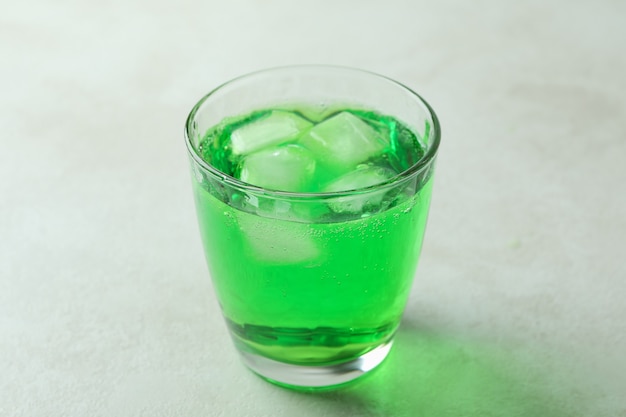 Verre de soda vert sur une surface texturée blanche