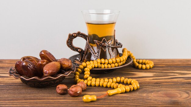 Photo verre à thé avec fruits de dattes séchées et chapelet