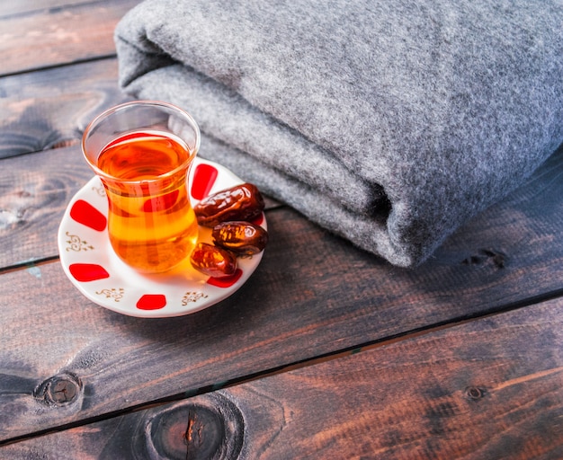 Un verre de thé noir et des dates sur une soucoupe