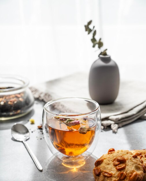 Un verre de tisane et des biscuits faits maison sur le fond d'une fenêtre avec la lumière du soleil du matin