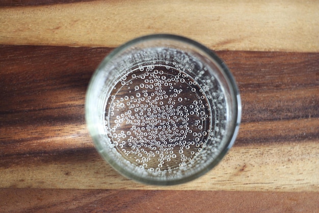 Un verre transparent avec soda se dresse sur une boisson rafraîchissante de table en bois