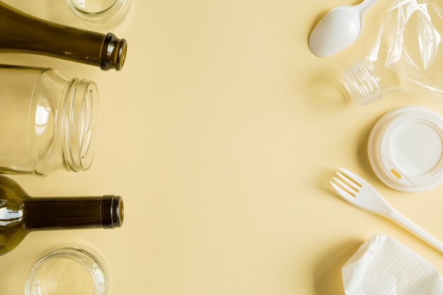 Verre trié secondaire et poubelle en plastique sur fond jaune. Déchets pour le recyclage vue de dessus sur fond de papier jaune avec espace de copie.