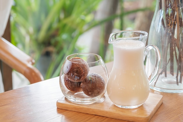 Un verre de trois boules de café glacé sur un plateau en bois servi avec du lait, des rafraîchissements latte maison