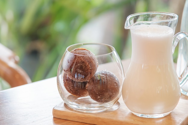 Un verre de trois boules de café glacé sur plateau en bois servi avec du lait