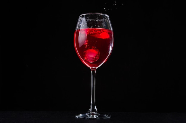 Un verre de vigne rouge sur fond noir. Verre à vin sur table sombre. Boisson au cabernet.