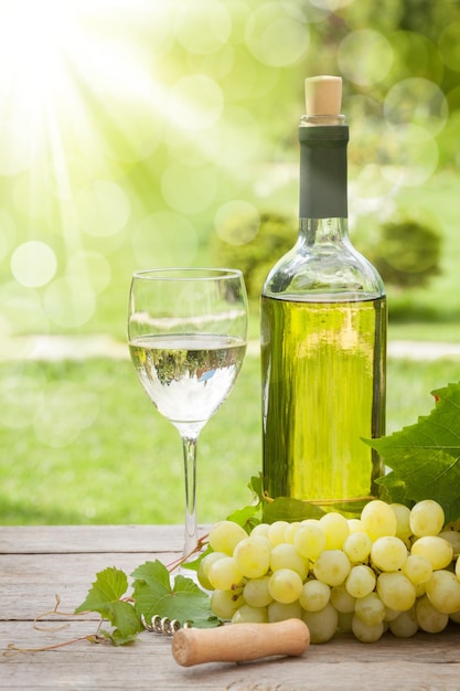 Verre à vin blanc et bouteille avec grappe de raisin