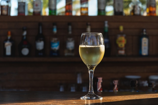 Verre de vin blanc sur le comptoir en bois avec la lumière du soleil.