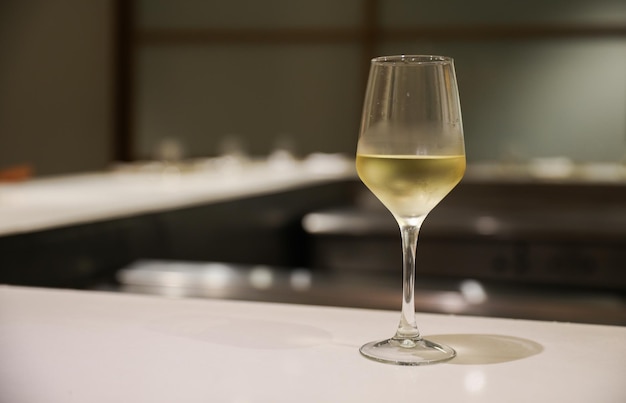 Un verre de vin blanc est assis sur un bar avec un bar en arrière-plan.
