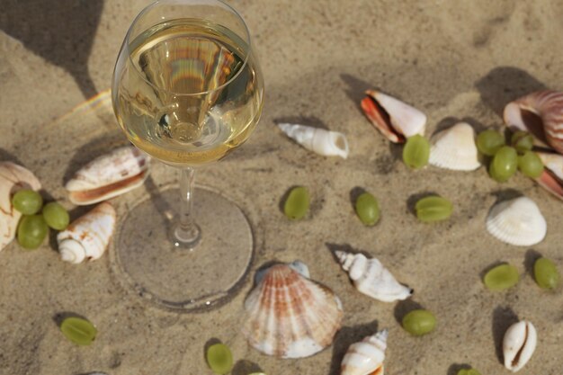 verre de vin blanc sur le sable en arrière-plan avec des coquillages