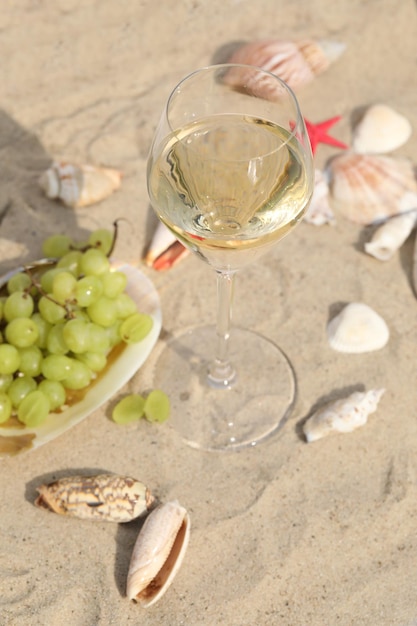 verre de vin blanc sur le sable en arrière-plan avec des coquillages