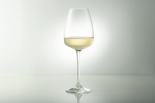 Un verre de vin blanc sur la table. Fond clair.