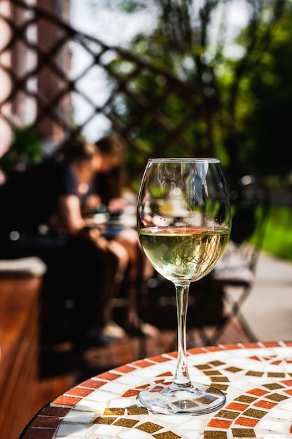 Un verre de vin blanc sur une table en pierre de mosaïque d'une terrasse de café sur une journée ensoleillée