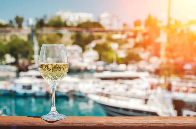 Verre de vin blanc avec en toile de fond la mer méditerranée et le port avec des yachts en tournée...