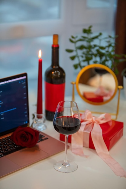 Verre de vin avec boîte-cadeau devant un ordinateur portable de rencontres en ligne