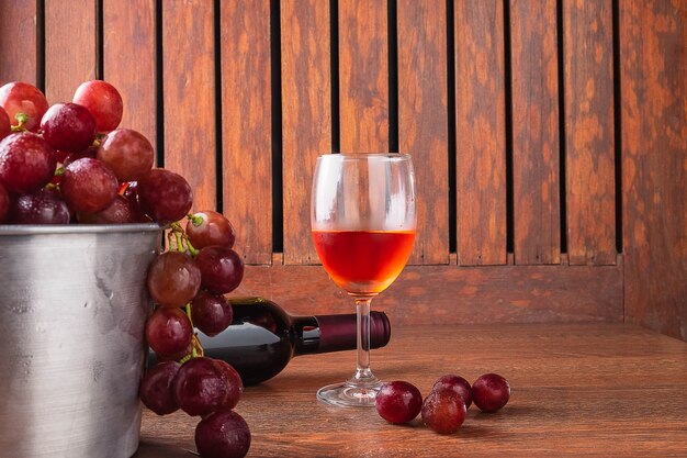 Verre à vin et bouteille de vin avec des raisins rouges sur fond en bois