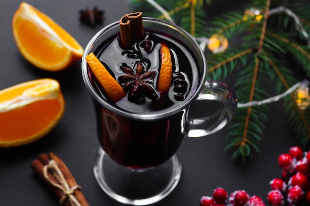 Verre de vin chaud à la cannelle, anis et oranges sur un fond de Noël festif.