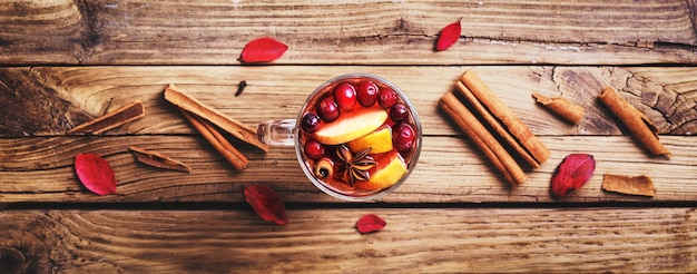 Verre de vin chaud avec des ingrédients sur une table en bois