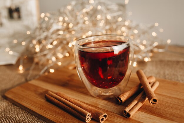 Verre de vin chaud sur une souche en bois avec des bâtons de cannelle