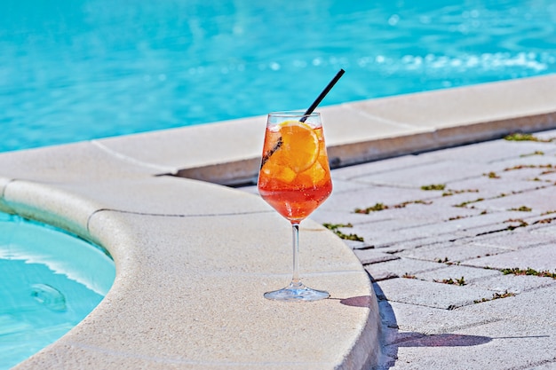 Verre à vin de cocktail froid Aperol spritz contre l'eau turquoise de la piscine