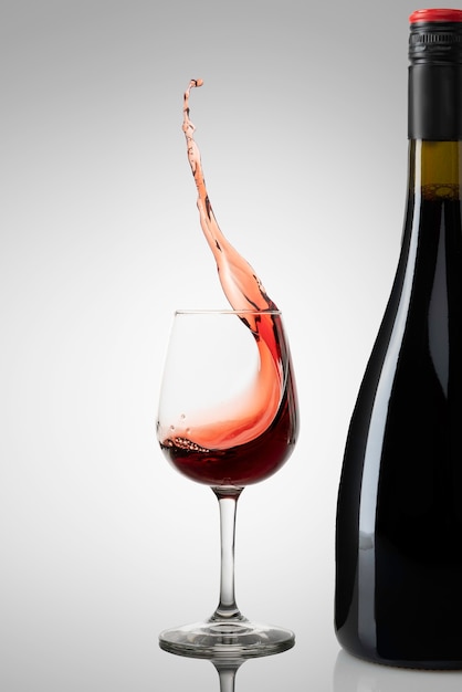 Verre à vin avec éclaboussures ou vin et bouteille en mouvement